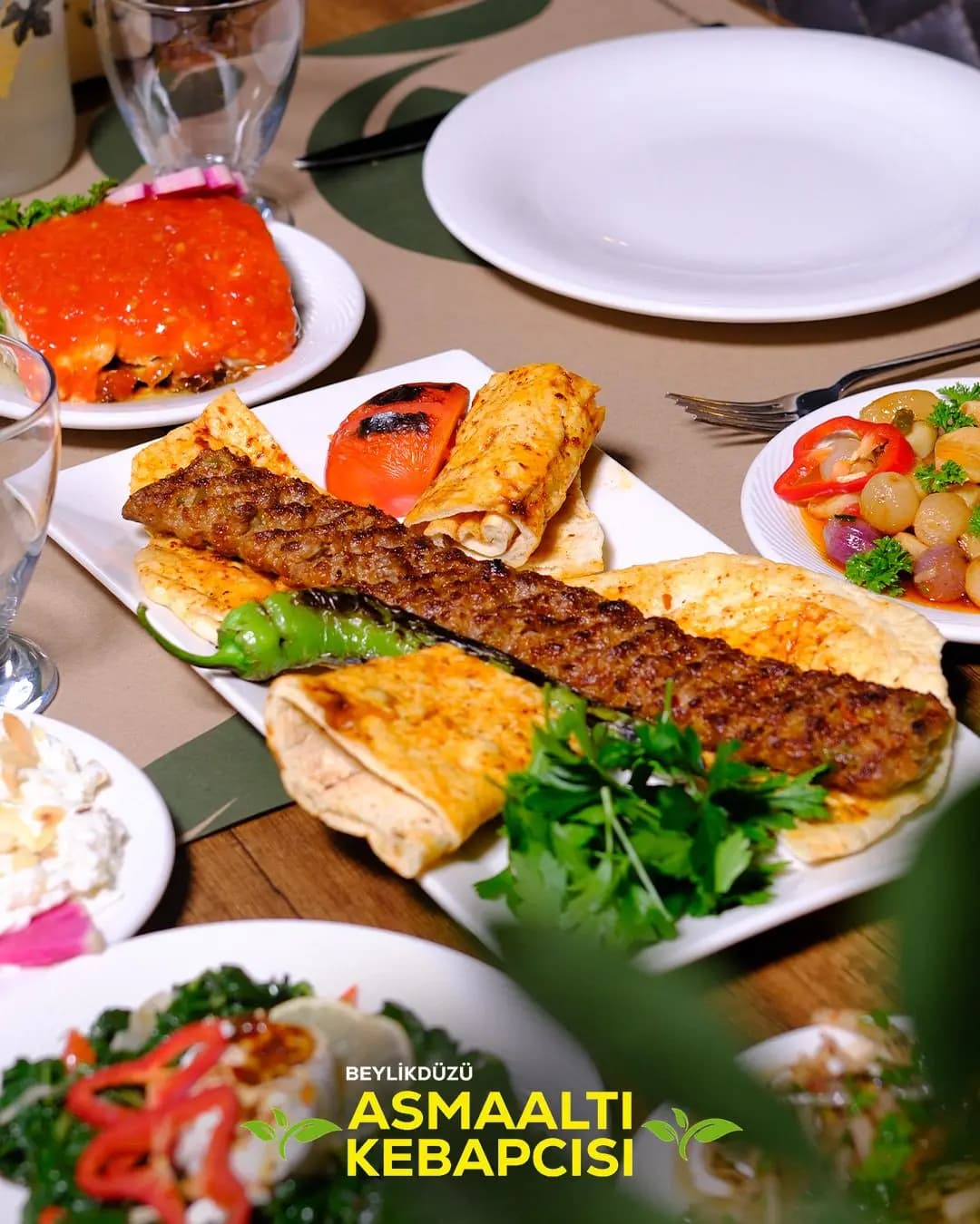 Lavaş üzerinde közde pişmiş Adana kebap, közlenmiş domates-biber ve mezeler